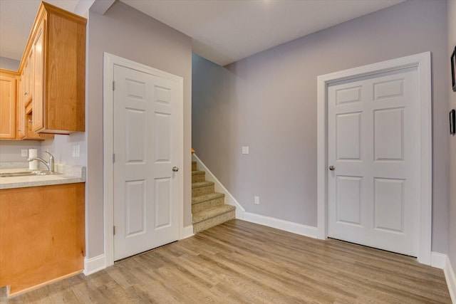 interior space featuring light wood finished floors, stairway, a sink, and baseboards