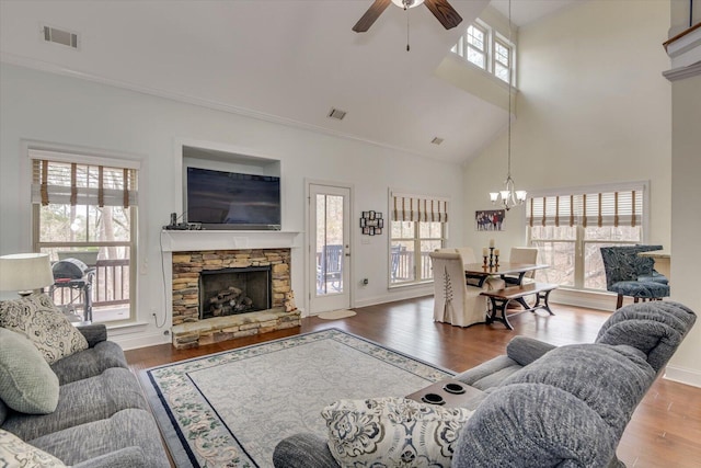 living room with visible vents, dark wood finished floors, a stone fireplace, and baseboards