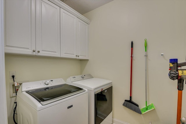 clothes washing area featuring cabinet space and washing machine and clothes dryer