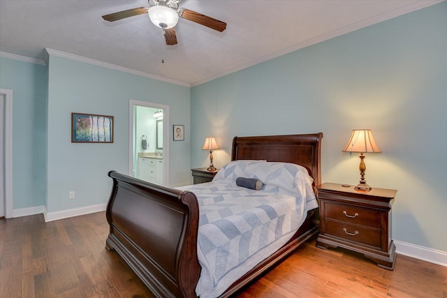 bedroom with ornamental molding, ensuite bath, wood finished floors, and baseboards