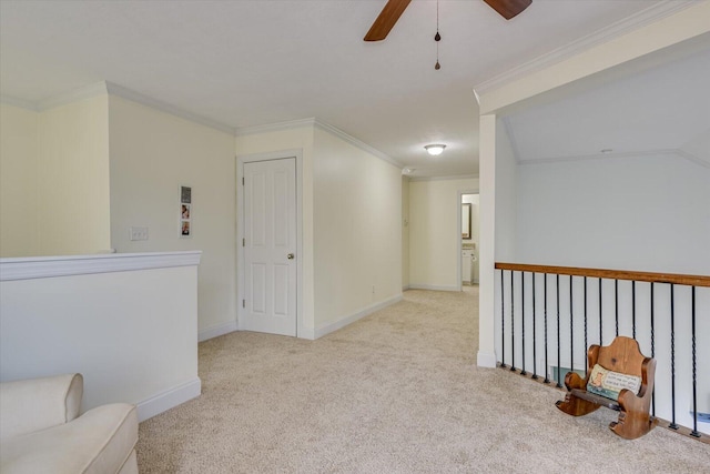 spare room with a ceiling fan, light carpet, crown molding, and baseboards