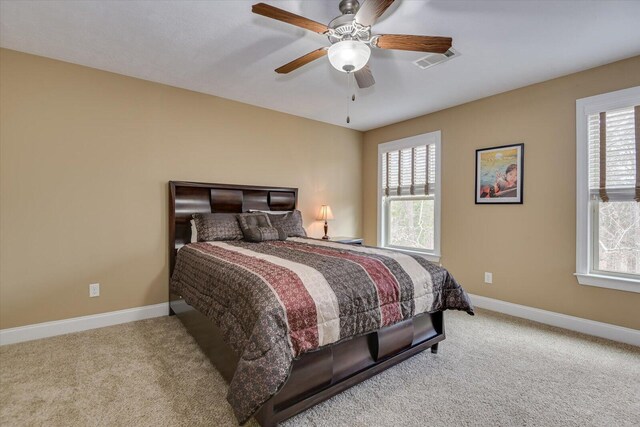 bedroom featuring light carpet, visible vents, baseboards, and multiple windows