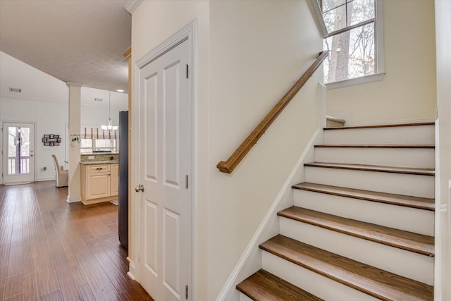 staircase with visible vents, decorative columns, baseboards, and wood finished floors