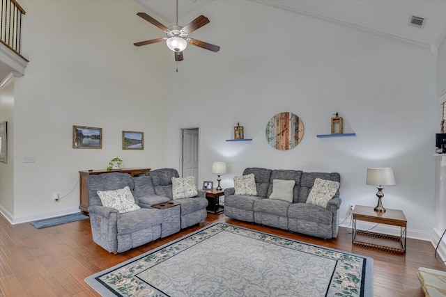 living area featuring baseboards, visible vents, a ceiling fan, wood finished floors, and high vaulted ceiling