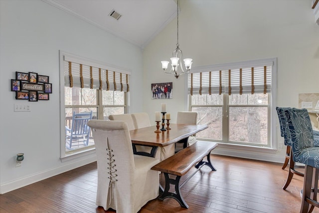 dining area with baseboards, visible vents, wood finished floors, an inviting chandelier, and high vaulted ceiling