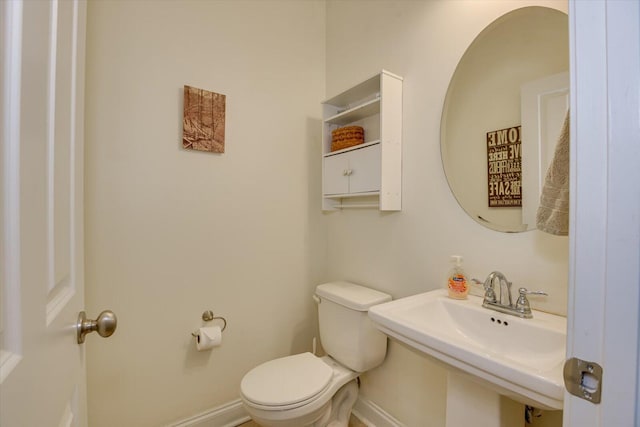 bathroom with toilet, baseboards, and a sink