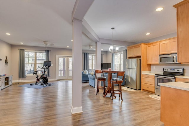 kitchen featuring light wood finished floors, open floor plan, stainless steel appliances, light countertops, and light brown cabinets