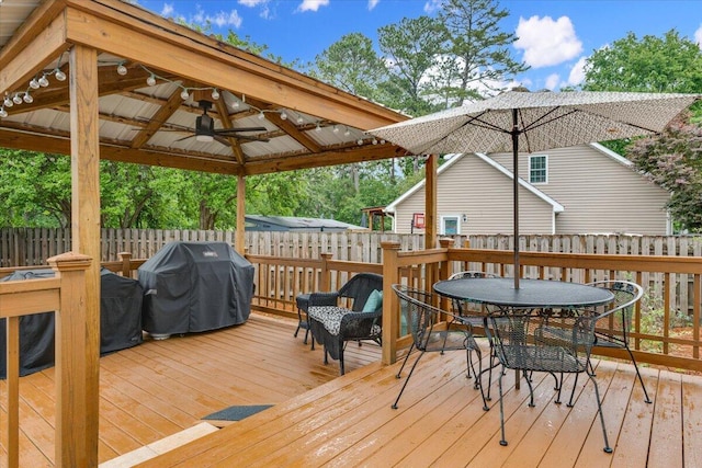 wooden terrace featuring a gazebo, a grill, fence, and outdoor dining area