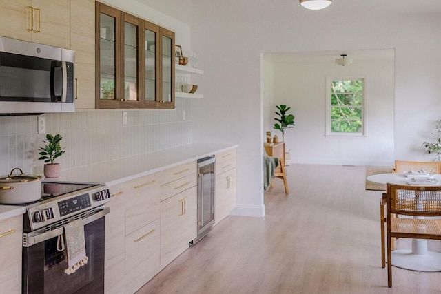 115 W St, Thomson, GA 30824 - kitchen with appliances with stainless steel finishes, beverage cooler, light countertops, and light wood-type flooring