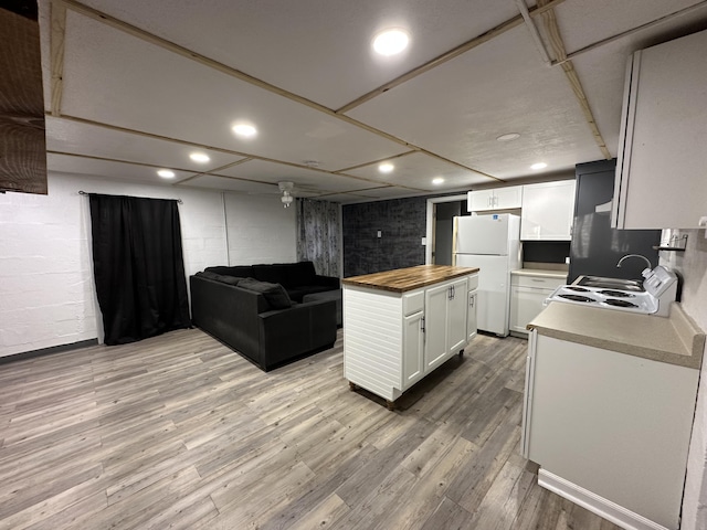 kitchen with butcher block countertops, light wood-type flooring, white cabinets, and white refrigerator