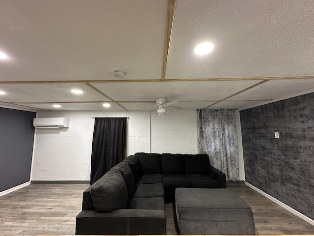 living room with hardwood / wood-style floors, a wall mounted AC, and ceiling fan