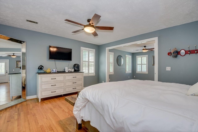 bedroom with ceiling fan, a textured ceiling, and light wood-type flooring