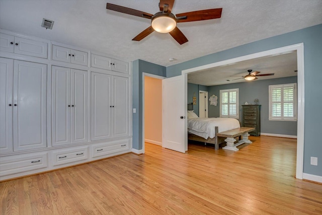 bedroom with a textured ceiling, light hardwood / wood-style flooring, and ceiling fan