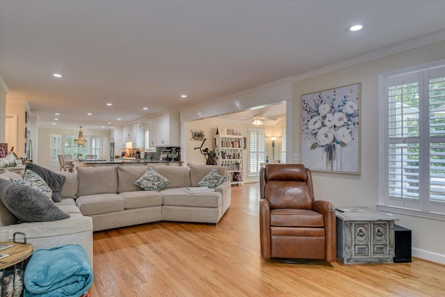 living room with a healthy amount of sunlight, light wood-type flooring, ceiling fan, and ornamental molding