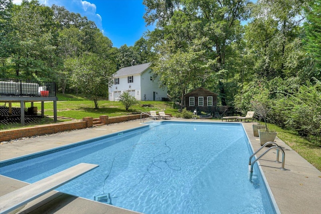 view of swimming pool featuring a lawn and a diving board