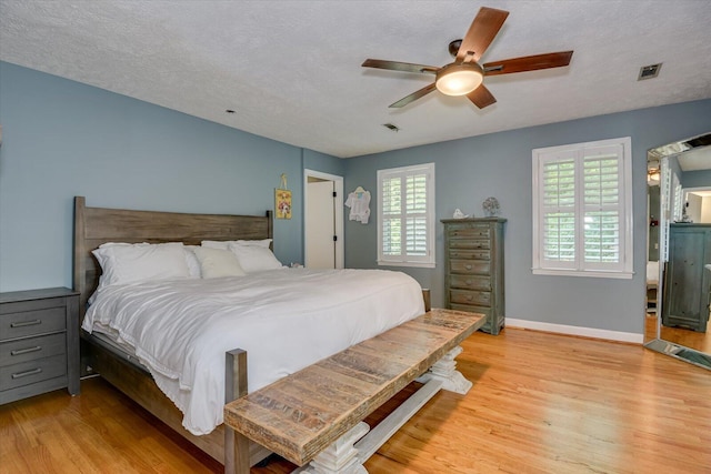 bedroom with ceiling fan, light hardwood / wood-style floors, and a textured ceiling