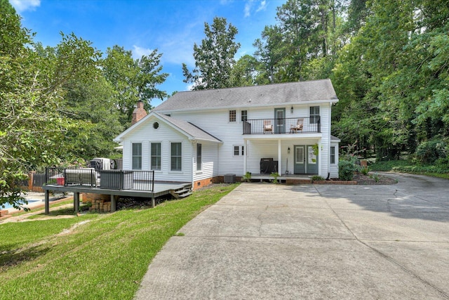 view of front of property with a balcony, a front lawn, and central air condition unit