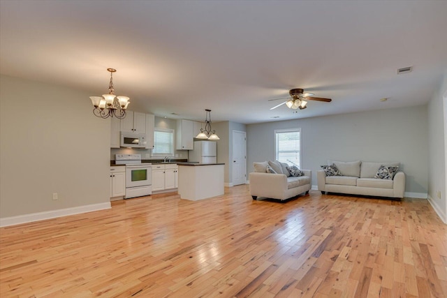 unfurnished living room featuring sink, ceiling fan with notable chandelier, and light wood-type flooring