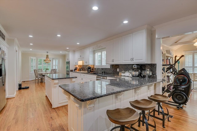 kitchen featuring dark stone countertops, white cabinets, hanging light fixtures, and a kitchen island