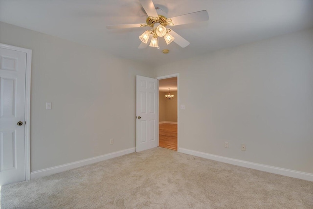 carpeted empty room with ceiling fan with notable chandelier