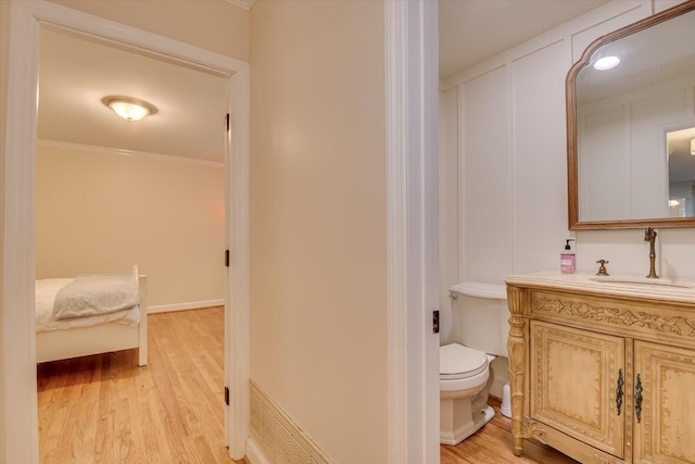 bathroom with hardwood / wood-style floors, vanity, toilet, and crown molding