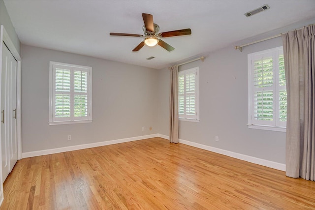 unfurnished bedroom featuring ceiling fan, a closet, light hardwood / wood-style flooring, and multiple windows