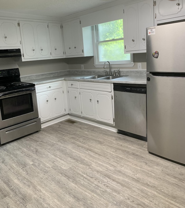 1921 Fenwick St, Augusta, GA 30904 - kitchen with stainless steel appliances, range hood, light wood-type flooring, white cabinetry, and light countertops