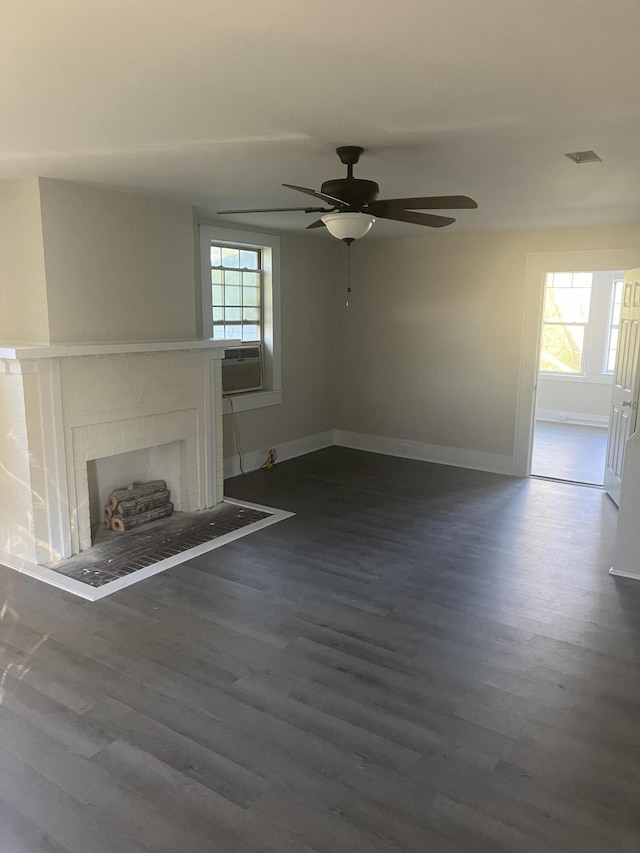 unfurnished living room with ceiling fan, plenty of natural light, cooling unit, and dark wood-type flooring