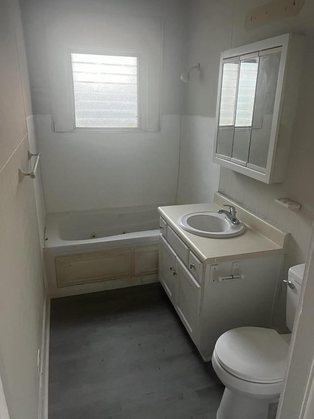 bathroom with a wealth of natural light, vanity, toilet, and a bathtub