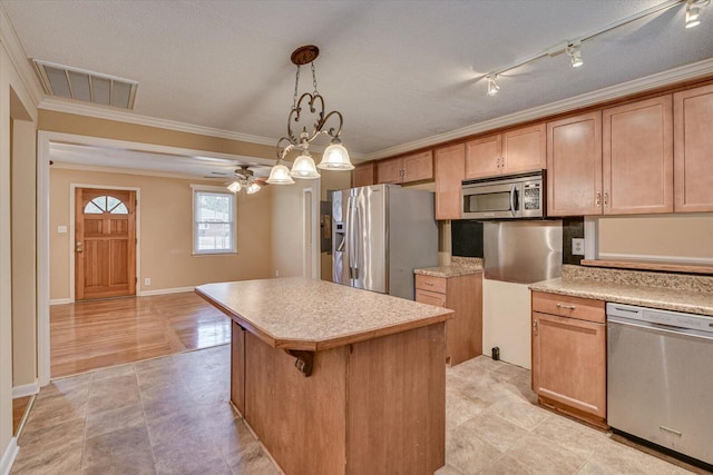 kitchen featuring visible vents, appliances with stainless steel finishes, a center island, light countertops, and crown molding