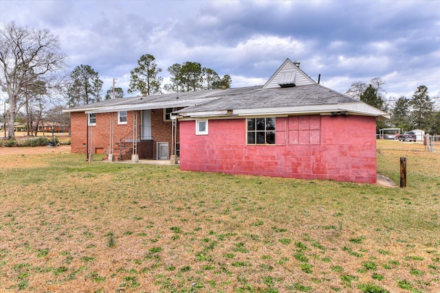 rear view of house featuring concrete block siding and a lawn