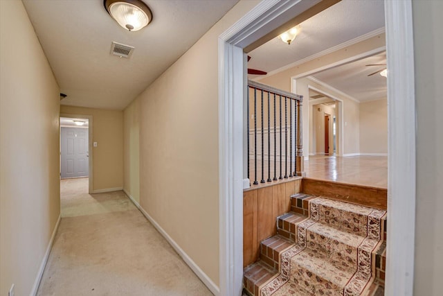 hallway with ornamental molding, light colored carpet, visible vents, and baseboards