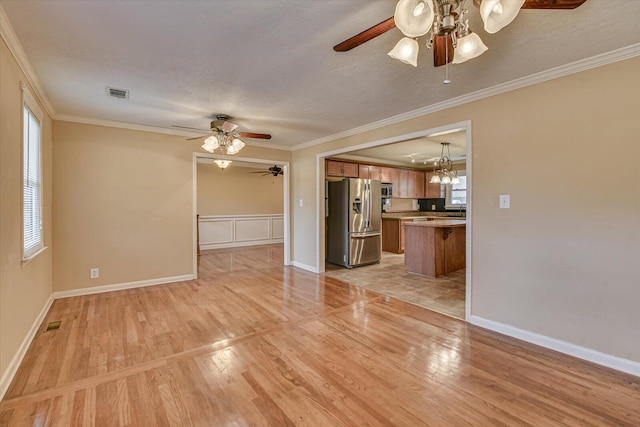 unfurnished living room with baseboards, crown molding, and light wood finished floors