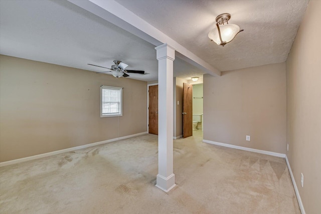 spare room featuring baseboards, light colored carpet, a textured ceiling, and ornate columns