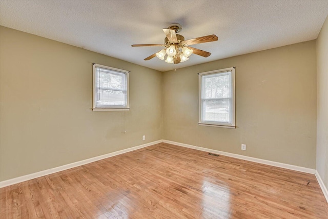 unfurnished room featuring baseboards, plenty of natural light, visible vents, and light wood-style floors