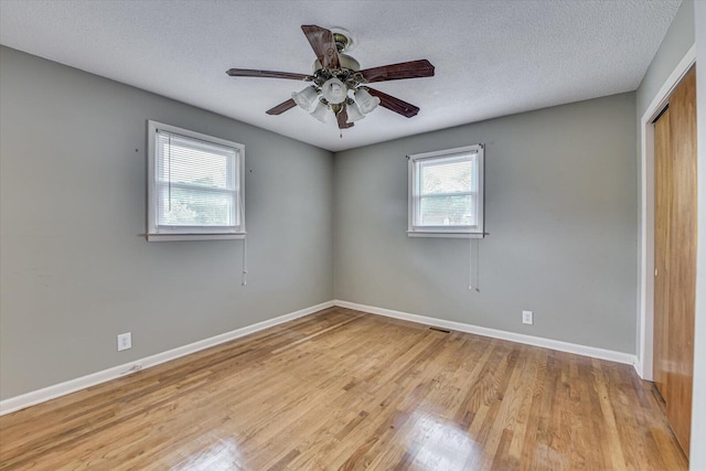 unfurnished bedroom featuring a closet, ceiling fan, a textured ceiling, wood finished floors, and baseboards