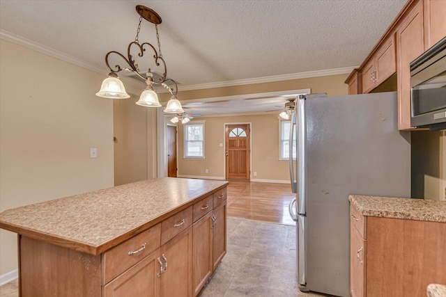 kitchen featuring ceiling fan, appliances with stainless steel finishes, a center island, light countertops, and crown molding