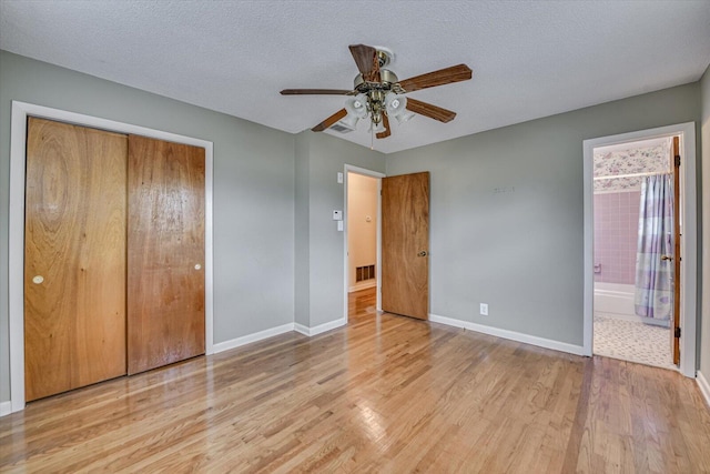 unfurnished bedroom with a textured ceiling, a closet, baseboards, and wood finished floors