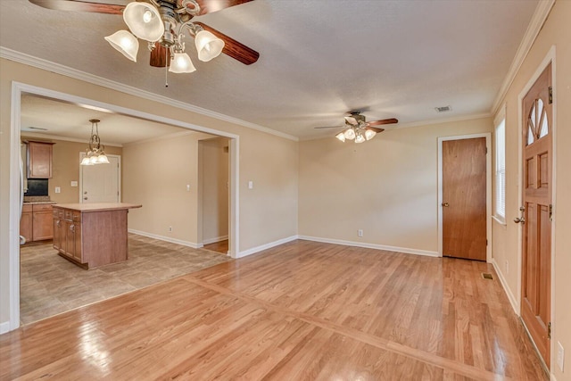 unfurnished living room featuring light wood-style floors, visible vents, baseboards, and crown molding