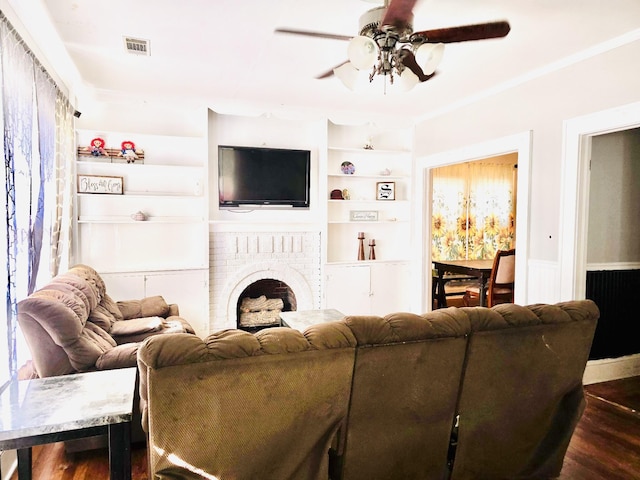 living room with built in shelves, ceiling fan, dark hardwood / wood-style flooring, and a brick fireplace