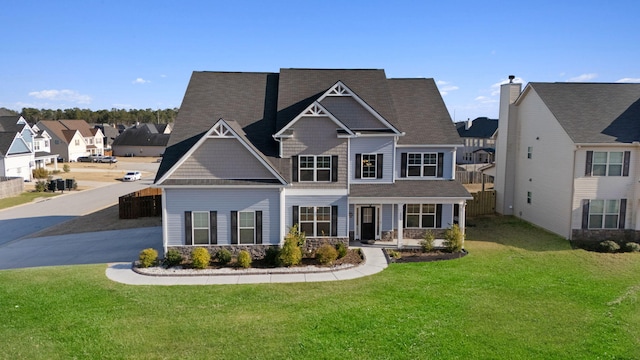 craftsman-style home featuring stone siding, a residential view, fence, and a front lawn