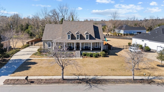 new england style home with covered porch, fence, and concrete driveway