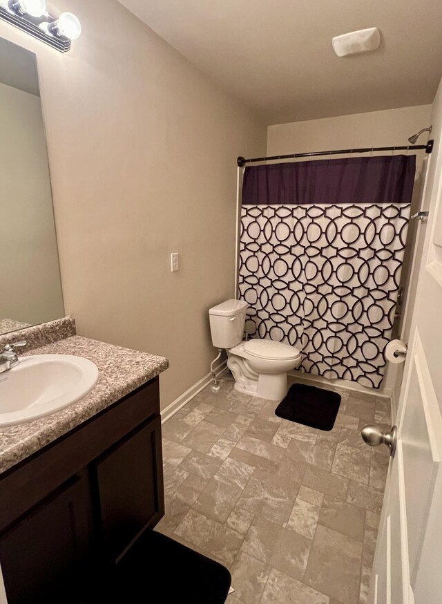 bathroom featuring vanity, toilet, and curtained shower