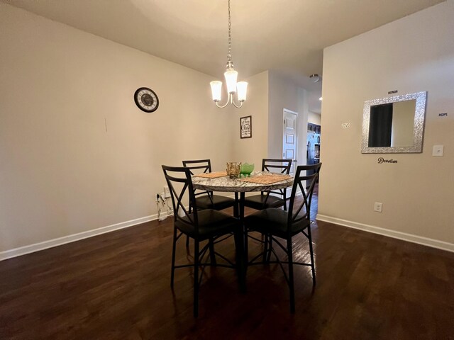 dining space with dark wood-type flooring and an inviting chandelier