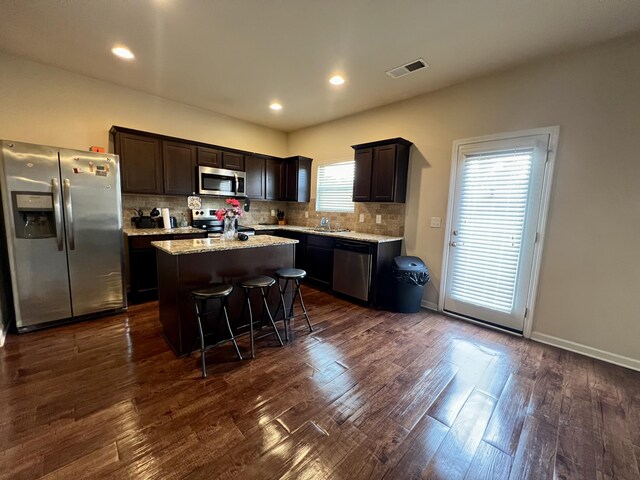 kitchen featuring appliances with stainless steel finishes, a breakfast bar, dark wood-type flooring, sink, and a kitchen island