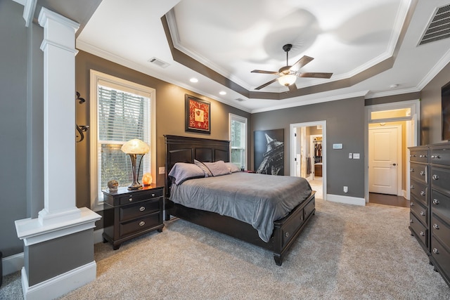 bedroom featuring visible vents, light colored carpet, a raised ceiling, and decorative columns