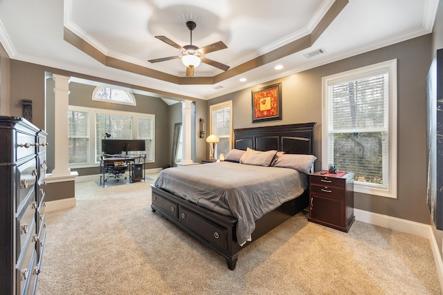 bedroom with crown molding, baseboards, light colored carpet, a tray ceiling, and ornate columns