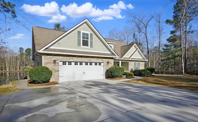 view of front of property featuring stone siding, concrete driveway, and a shingled roof