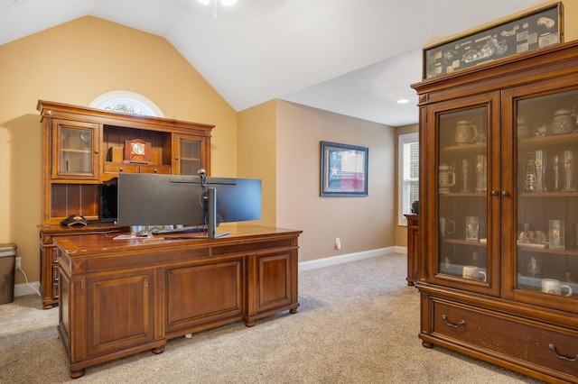 home office with vaulted ceiling, baseboards, and light carpet