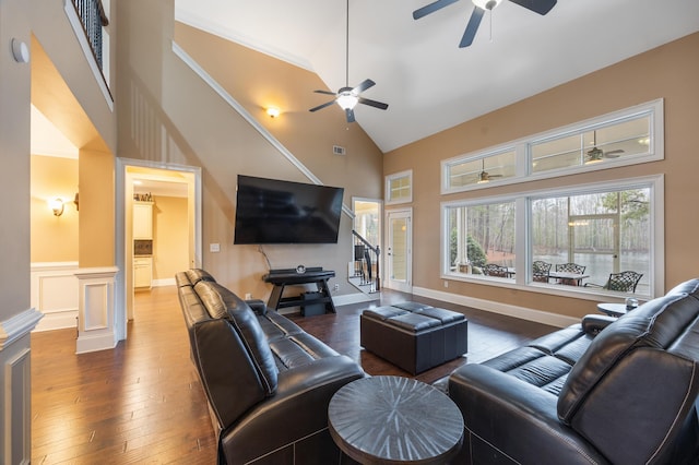 living area with stairway, high vaulted ceiling, ceiling fan, wood-type flooring, and wainscoting